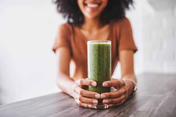 Persona sosteniendo un batido verde nutritivo, símbolo de bienestar y suplementos dietarios Neumed