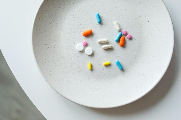 Plato blanco con cápsulas y comprimidos de colores que representan los medicamentos de Neumed